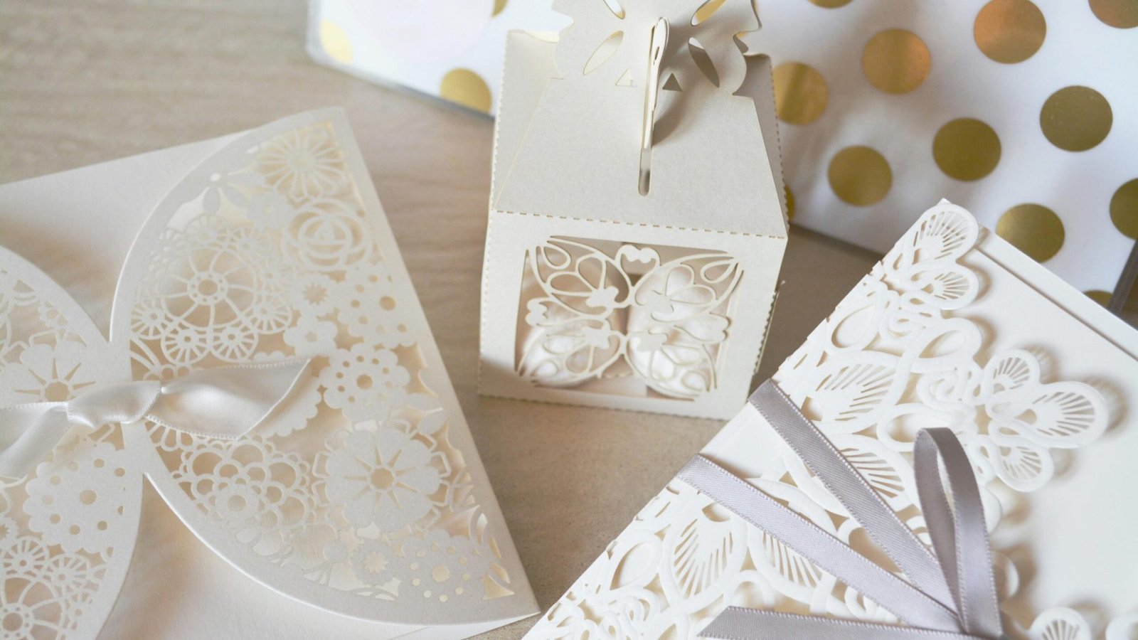 Beautiful laser cut invitations and gift box with intricate designs and ribbons, perfect for weddings or special events.